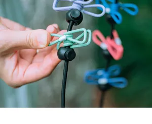 Portable travel clothesline detail showing elastic rope with colorful metal clips and adjustable stoppers.