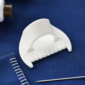 Precision sewing darning tool detail, white plastic edge guide accessory for DIY crafting.