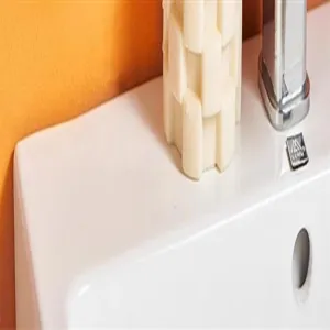 Bathroom tissue box accessory detail shot showcasing premium ceramic basin surface and metallic faucet.