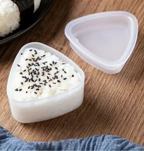 Vue en gros plan d'un moule a boules de riz triangulaire transparent avec du riz.