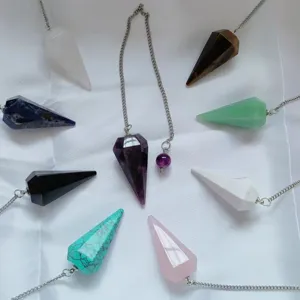Detailweergave van diverse natuurlijke kristallen pendels op een witte stoffen ondergrond.