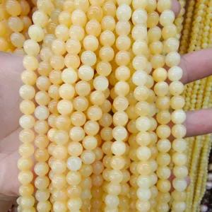 Dettagli di perle tonde in pietra gialla, ideali per la creazione di gioielli fai da te unici.