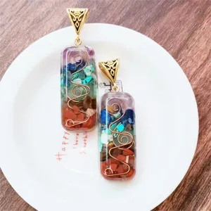 Close-up detail of colorful crushed stone resin pendant with copper wire wrapping on plate.