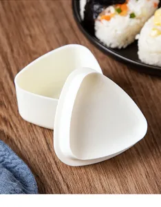 Gros plan de moule à boulettes de riz triangulaire blanc sur bois avec onigiri.