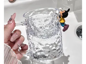 Transparent textured mouthwash cup with cute cartoon character figurine, stylish home toothbrush holder.