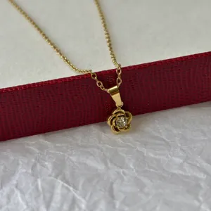 Vue rapprochée détaillée d'un élégant collier en fleur de camélia doré avec pierre centrale