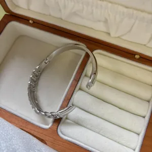 Macro view of silver stainless steel knotted open bangle in a plush wooden jewelry box