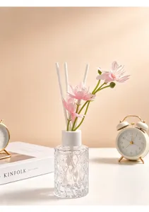 Detailansicht eines Reed-Diffusors aus Kristallglas mit rosa Blumen und Stäben