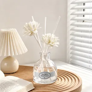 Conjunto de difusor de aroma minimalista con varillas de flores blancas y botella de vidrio.