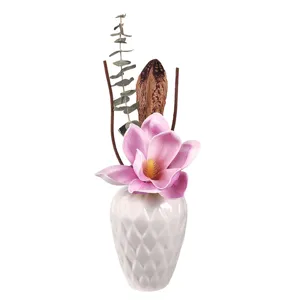 Jarrón difusor de aroma de cerámica blanca con flor de magnolia rosa y arreglo botánico seco.
