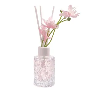 Elegantes Reed-Diffusor-Set mit künstlichen rosa Blumen und Glasflasche mit Textur