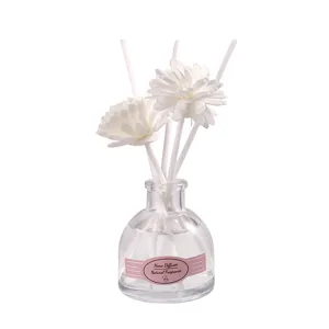 Difusor de aromas para el hogar con varillas y flores blancas en botella de vidrio.