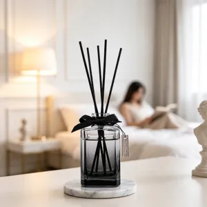 Modern Nordic style reed diffuser bottle with black sticks and marble base for home decor.