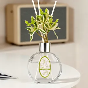 Glas-Diffusor-Flasche mit künstlicher grüner Pflanze und weißen Stäbchen für Zuhause