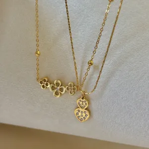 Close-up detail of minimalist stainless steel gold flower and heart pendant necklaces