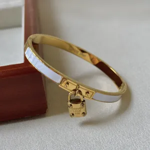 Nahaufnahme eines goldenen Edelstahlarmbands mit Vorhängeschloss und Gravur