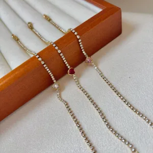 Primo piano di eleganti bracciali tennis dorati con accenti di cristallo a cuore