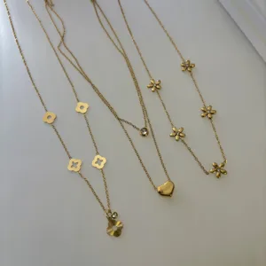 Detailed view of elegant gold stainless steel necklaces with heart and flower charms.