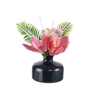 Reed diffuser floral arrangement with black bottle and pink orchids for home decoration style