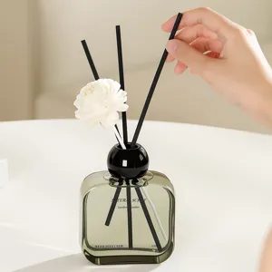 Modern square glass reed diffuser bottle with black cap and floral sticks for home room decor.