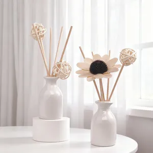 Minimalistische weiße Keramikvasen mit Holzsonnenblume und Rattanstäbchen für die Dekoration.
