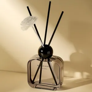 Glass reed diffuser bottle with black sticks and flower, home fragrance for bedroom and living room.