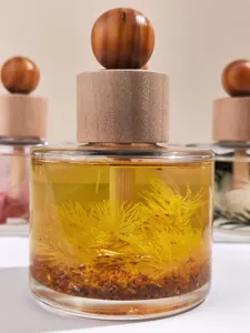 Close-up detail of the wooden ball diffuser bottle, showcasing clear liquid and floating botanical.