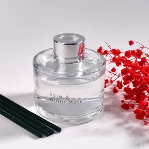 Frasco difusor de aroma de vidrio transparente con varillas negras y flores secas rojas