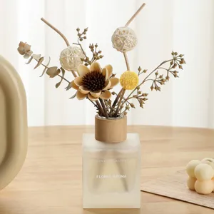 Elegante difusor de varillas con flores secas en frasco de vidrio esmerilado.