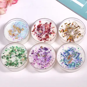 Close-up detail of handmade scented tealight candles with dried flowers and crystals in jars.