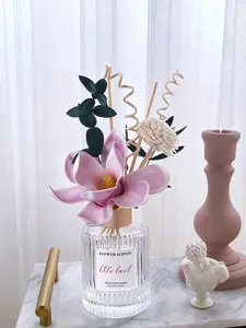 Decorative reed diffuser with pink flower and green leaves for home living room fragrance.