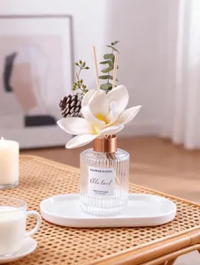 Detail view of a luxury reed diffuser with white flower, rattan table background, cozy home