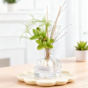Home fragrance reed diffuser set with decorative green dried flowers and clear glass bottle.