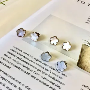 Détail macro de boucles d'oreilles fleurs en nacre blanche sur une page de magazine