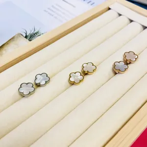 Gros plan de boucles d'oreilles fleurs en nacre en finitions argent, or et or rose