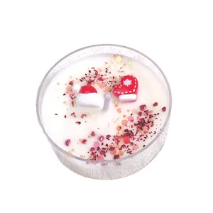 Vela navideña artesanal de cera de soja con decoraciones de mitones y gorros rojos
