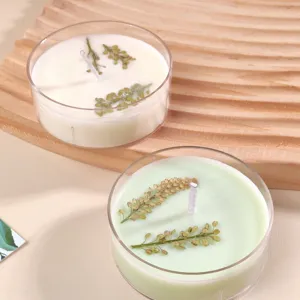 Scented candles in clear round boxes decorated with dried botanical flowers, natural wax style.