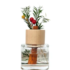 Close-up van diffuserfles met houten dop, gedroogde bloemen en geurvloeistof detail.