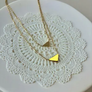 Detailansicht einer zweilagigen goldenen Edelstahlkette mit Dreiecksanhängern.