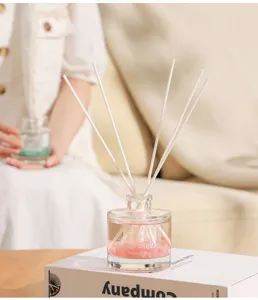 Elegante difusor de varillas con piedras rosas en botella sobre un libro blanco.