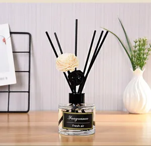 Reed diffuser glass bottle with black sticks and flower decor for home fragrance.