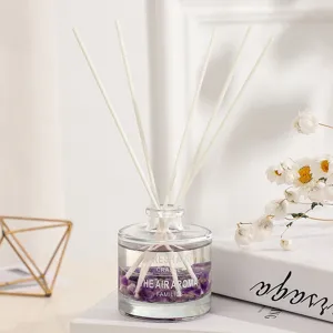 Elegante difusor de varillas de vidrio con piedras de cristal moradas y varas blancas
