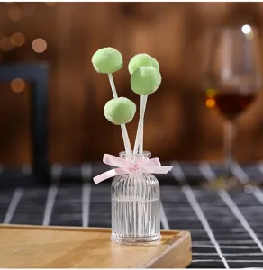 Fireless aroma reed diffuser with green fluffy ball and pink ribbon bottle detail view.
