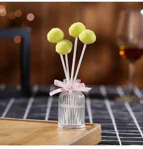 Flameless aroma diffuser bottle with yellow fluffy ball sticks and pink ribbon bow detail