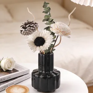 Jarrón de cerámica negra con flores secas y difusor para la decoración del hogar moderno.