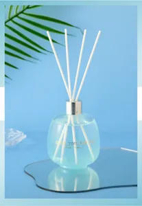 Detail shot of reed diffuser with blue liquid, silver cap, and white sticks in cozy setup.