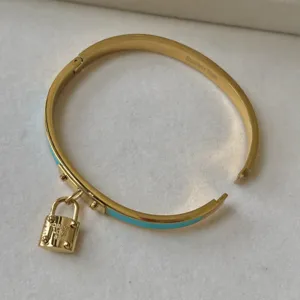 Luxuriöser goldener Edelstahlreif mit blauem Emailleschmuck und einem Schlossanhänger.