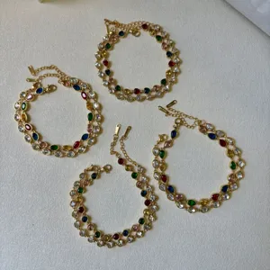 Close-up of gold-plated steel bracelets featuring colorful teardrop and round zircon stones