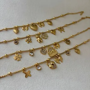 Detail van gouden roestvrijstalen armbanden met vlinder-, klaver- en hartpendants