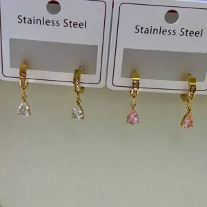 Close-up of stainless steel hoop earrings with waterdrop zirconia pendants in gold finish.